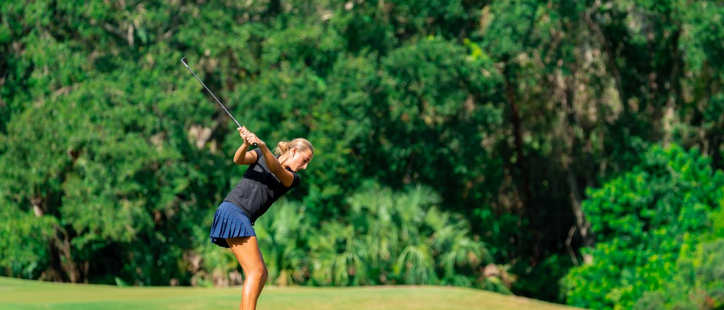 A DME golfer at the top of the follow-through after a tee shot.
